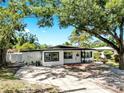 Well-maintained single-story home with black trim windows and a spacious driveway, complemented by lush trees at 4112 W Lawn Ave, Tampa, FL 33611