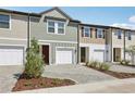 Townhome exterior featuring attached garages, brick driveway, and colorful siding details at 7683 Deer Valley Circle, Tampa, FL 33635