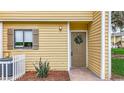 Close-up of a condo entrance featuring a wreath-adorned door, neat landscaping, and a well-maintained exterior at 22706 Gage Loop # 31, Land O Lakes, FL 34639