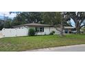 A cozy, well-kept house with a new white fence, lush green lawn and mature landscaping at 1027 Fountainhead Dr, Largo, FL 33770