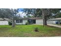 Inviting home with green lawn, complemented by mature trees and a white perimeter fence at 1027 Fountainhead Dr, Largo, FL 33770