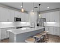 Modern kitchen featuring white cabinetry, stainless steel appliances, a center island and stylish pendant lights at 19259 Mossy Pine Dr, Tampa, FL 33647