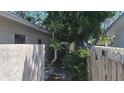 View of the side yard with wood and concrete fences and mature trees at 2502 Tropical Shores Se Dr, St Petersburg, FL 33705