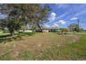Expansive front lawn with mature trees surrounding a charming single-story home at 3009 Ainsworth Ave, Spring Hill, FL 34609