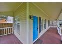 Close up of a charming front porch featuring wood floors, a bright blue door, and exterior sconces at 3906 W San Luis St, Tampa, FL 33629
