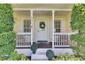 Quaint front porch featuring decorative columns, a wreath-adorned door, and manicured greenery enhancing its appeal at 4312 James L Redman Pkwy, Plant City, FL 33567