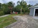 A wide concrete driveway beside a home with a garage and a shed in the grassy backyard at 820 Crenshaw Lake Rd, Lutz, FL 33548