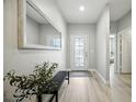 Bright entryway featuring a decorative front door, light wood floors, bench, and a large mirror at 3025 Winglewood Cir, Lutz, FL 33558