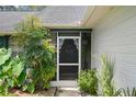 Close-up of a cozy front porch with decorative accents, lush plants, and screened door at 5301 Bayonne Ave, Spring Hill, FL 34608