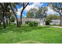 Well-manicured front yard with mature trees shading a white single Gathering home with attached garage at 5301 Bayonne Ave, Spring Hill, FL 34608