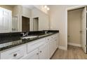 Bathroom featuring double sinks with granite countertops, white cabinets, and neutral wall colors at 5909 Bibb Ct, North Port, FL 34288