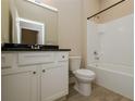 Well-lit bathroom with white cabinets, black granite countertops, and a shower-tub combo at 5909 Bibb Ct, North Port, FL 34288