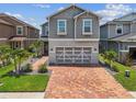 Beautiful gray two-story home with brick paver driveway, a two-car garage, and tropical landscaping at 8148 Artisan Cir, Seminole, FL 33777