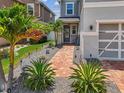 View of the entrance and garage with brick pavers, lush landscaping, and gray stone at 8148 Artisan Cir, Seminole, FL 33777