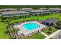 Aerial view of a sparkling community pool surrounded by lush landscaping and comfortable lounge seating at 9768 Pembrooke Pines Dr, Sun City Center, FL 33573
