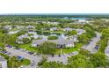 Aerial view of a condo complex featuring a central pond, mature trees, and ample parking spaces at 1207 Pine Ridge W Cir # H2, Tarpon Springs, FL 34688