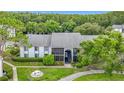 A lovely exterior view of a light colored condo building surrounded by trees and green space at 1207 Pine Ridge W Cir # H2, Tarpon Springs, FL 34688
