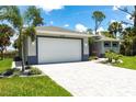 Angle view of a home showcasing a two-car garage, lovely landscaping, and a paved driveway at 14422 Chamberlain Blvd, Port Charlotte, FL 33953