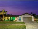 Charming single-story home featuring a well-manicured lawn, lush landscaping, and a striking teal front door at twilight at 1632 Ridge Top Way, Clearwater, FL 33765