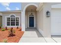 Stylish home entryway with a blue front door, an arched portico, and fresh landscaping at 1800 Loch Haven Ct, Trinity, FL 34655