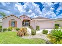 Inviting home exterior featuring a well-kept lawn, charming landscaping, and a two-car garage at 2226 N Creek Ct, Sun City Center, FL 33573