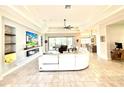Spacious living room featuring recessed lighting, tile floors, tray ceiling, and a large TV and entertainment center at 31889 Tortuga Shore Loop, Wesley Chapel, FL 33545