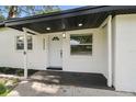 Welcoming front entry with decorative door, modern light fixture, and manicured landscaping at 4220 E Regnas Ave, Tampa, FL 33617