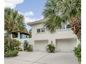 Exterior view of a two-story home with a two-car garage, white stucco and tropical landscaping at 831 Mandalay Ave, Clearwater, FL 33767