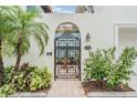 Wrought iron gate and archway leads to the home, landscaped with lush tropical plants and trees at 831 Mandalay Ave, Clearwater, FL 33767