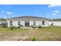 Back exterior of the home with sliding glass doors and windows overlooking a partially grassy backyard at 9429 Northcliffe Blvd, Spring Hill, FL 34606