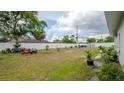 Large backyard enclosed with a white fence, featuring a mix of grass and young trees with lawn equipment at 9429 Northcliffe Blvd, Spring Hill, FL 34606