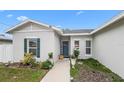 Inviting front porch with a blue front door, complemented by potted plants and updated landscaping features at 9429 Northcliffe Blvd, Spring Hill, FL 34606