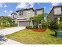 Well-manicured front yard with lush landscaping and a two-story home with gray exterior at 9440 Lemon Drop Loop, Sun City Center, FL 33573