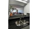 Close up of modern kitchen showcasing black granite counter, stainless sink, and open view to living area at 100 Bluff View Dr # 308A, Belleair Bluffs, FL 33770