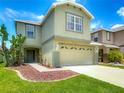 Two-story home featuring a two-car garage, manicured lawn, and beautiful landscaping at 12121 Tree Haven Ave, Gibsonton, FL 33534