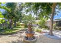 Serene backyard oasis featuring a charming fountain, mature trees, and meticulously maintained landscaping at 2201 Horan S Way, Gulfport, FL 33707