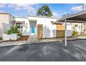 Charming home exterior features a white facade with an awning, modern wood detail, carport, and lush landscaping at 2240 Pinewood Villas Dr, Holiday, FL 34691