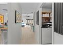 Bright hallway with wood floors leads to an open living space with sliding glass doors and a laundry area at 2240 Pinewood Villas Dr, Holiday, FL 34691