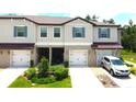 Townhouse exterior featuring a two-car garage, well-manicured landscaping, and a silver car in the driveway at 30798 Veridian Way, Wesley Chapel, FL 33543