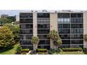 View of the building, showcasing multiple units with balconies, enhanced by lush, tropical palm trees at 3200 Cove Cay Dr # 5F, Clearwater, FL 33760
