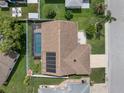 Aerial view of a home with a screened pool, solar panels, and a fenced yard at 7022 Kingsway Dr, Port Richey, FL 34668