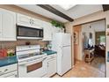 Kitchen with white appliances, cabinets and dark wood beams plus an adjacent living space at 855 Pinewood W Ter, Palm Harbor, FL 34683