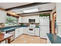 Bright kitchen features white cabinets, modern appliances, dark wood beams, and tile floors at 855 Pinewood W Ter, Palm Harbor, FL 34683