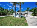 Inviting home featuring a lush lawn, tropical landscaping, and a circular driveway at 112 Peterson Ln, Palm Harbor, FL 34683