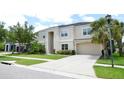 Tan two-story home with a two-car garage, mature landscaping, and a long driveway at 11408 Scribner Station Ln, Lithia, FL 33547