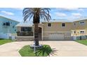 Tan two-story home with a palm tree in the front yard and a two-car garage at 17025 Dolphin Dr, North Redington Beach, FL 33708