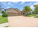 Charming home features a brick driveway, a two-car garage, and stone accents on the facade at 1830 Cameron Ct, Trinity, FL 34655