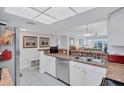 Well-lit kitchen with white cabinets, breakfast bar, and stainless steel dishwasher at 19029 Us Highway 19 N # 8-31, Clearwater, FL 33764