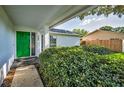 View of the home's entrance featuring a bright green front door and lush landscaping at 2559 Redwood Cir, Clearwater, FL 33763