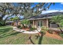 Charming brick home featuring a walkway with a double door entry and lush landscaping at 302 Old Mulrennan Rd, Valrico, FL 33594